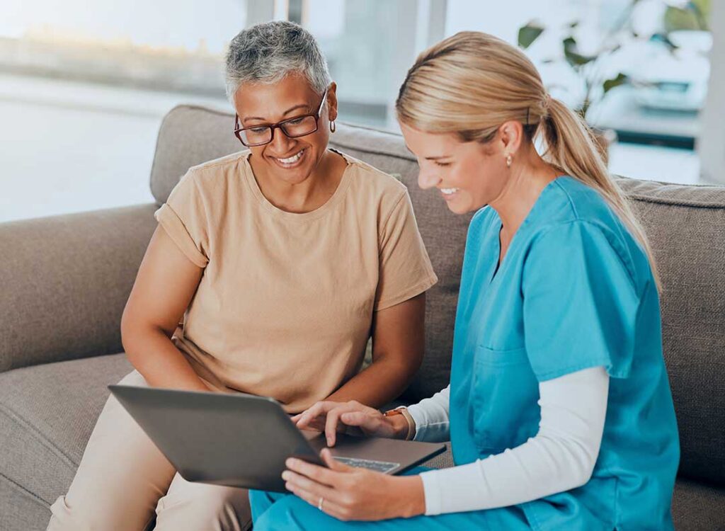 An older adult and a caregiver reviewing health paperwork together in a comfortable home-like setting.