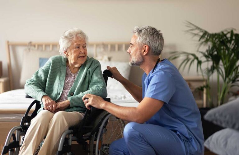 A senior adult unpacks familiar possessions with assistance in a bright assisted living apartment.