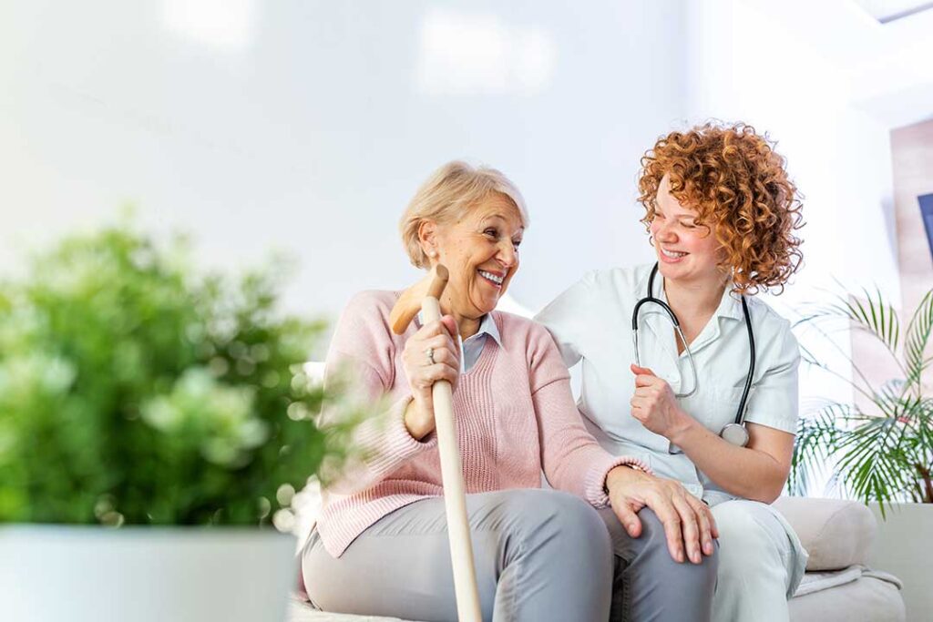 Older adults share a meal and conversation in a bright assisted living dining room.