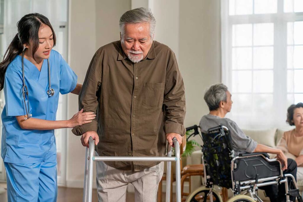 Two older adults sitting together at a small dining table, one smiling and the other engaged in a gentle conversation.