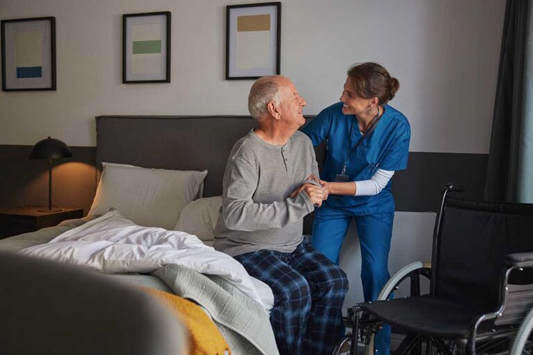 Older adults share a meal and conversation around a bright assisted living dining table.